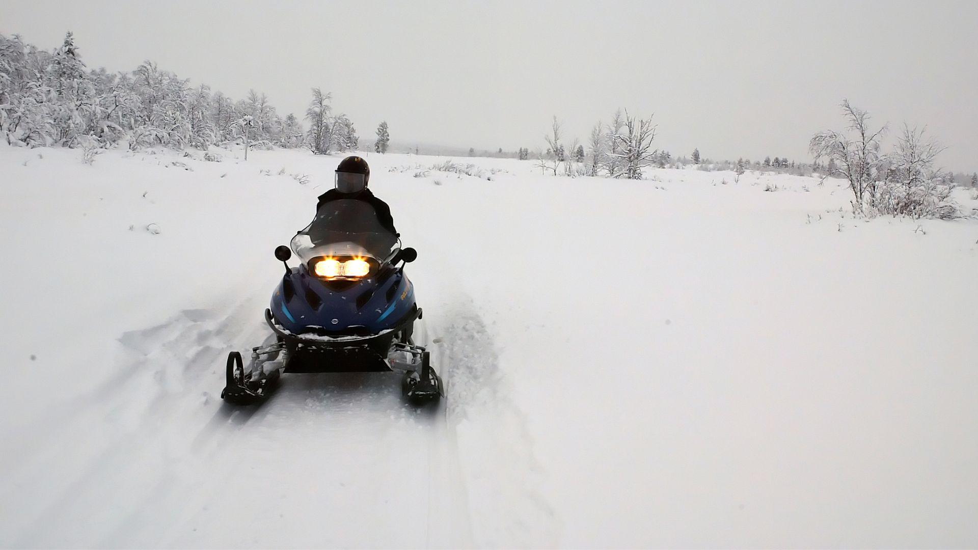 A person rides a snowmobile