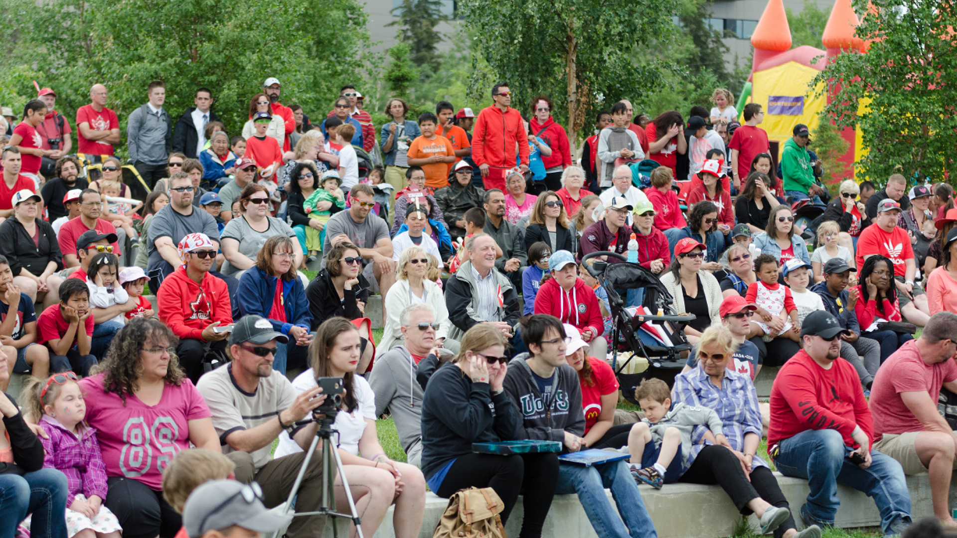 A crowd sits at the Canada Day festivities at Somba K'e Park