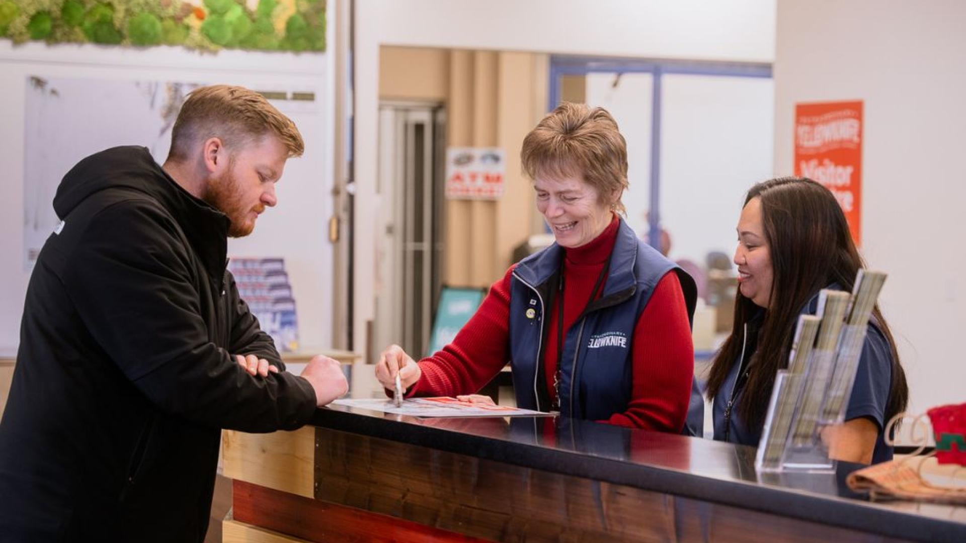 Two Visitor Centre Staff assisting a guest